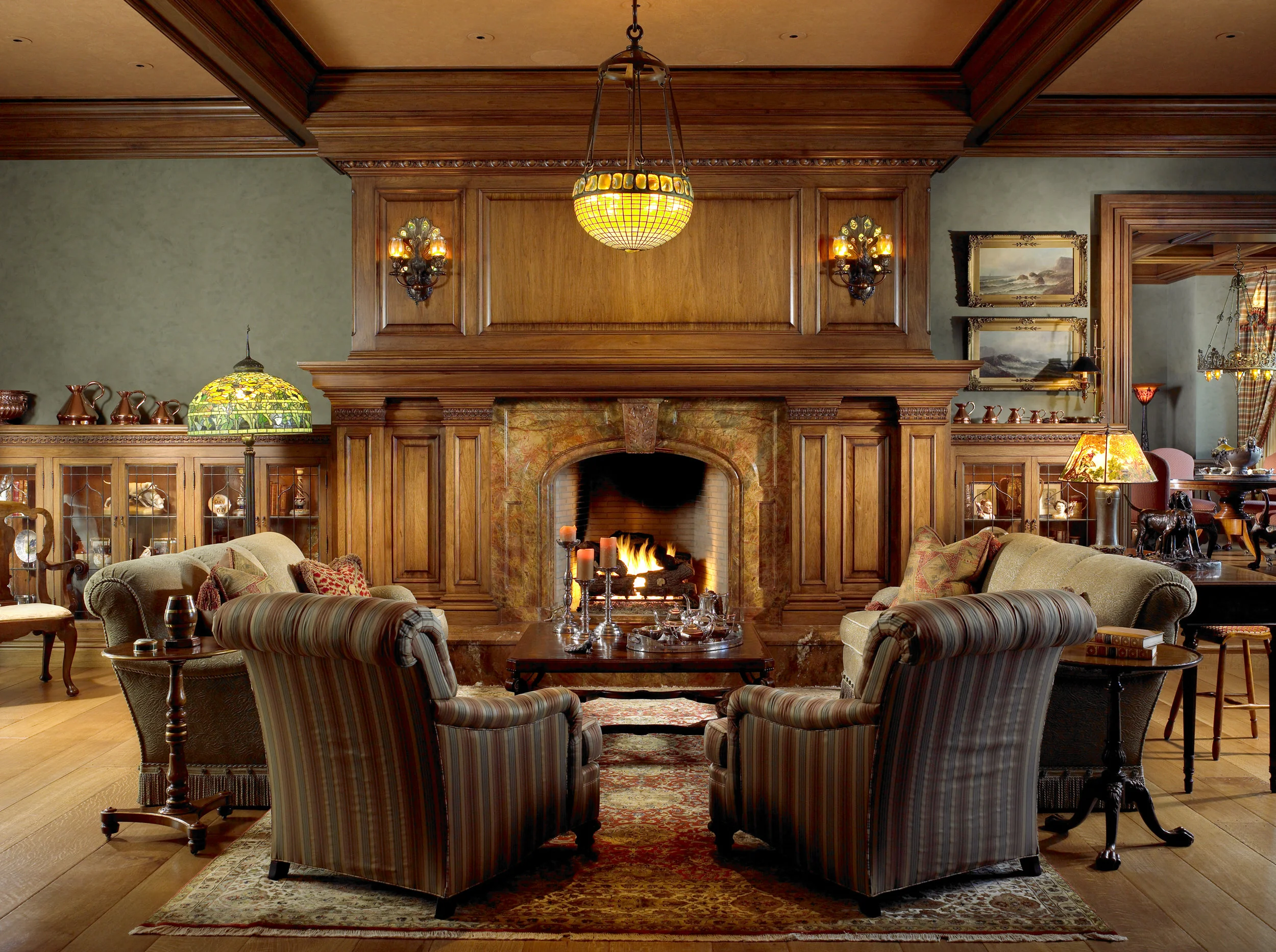 Grand custom wood-paneled living room with a carved fireplace, built-in cabinetry, and traditional furnishings.